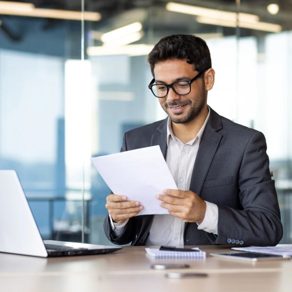 Man in suit reviewing papers at office desk.