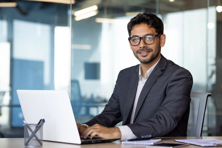 Young businessman working on a laptop in a modern office.
