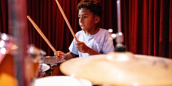 Young boy playing drums with focus and energy.
