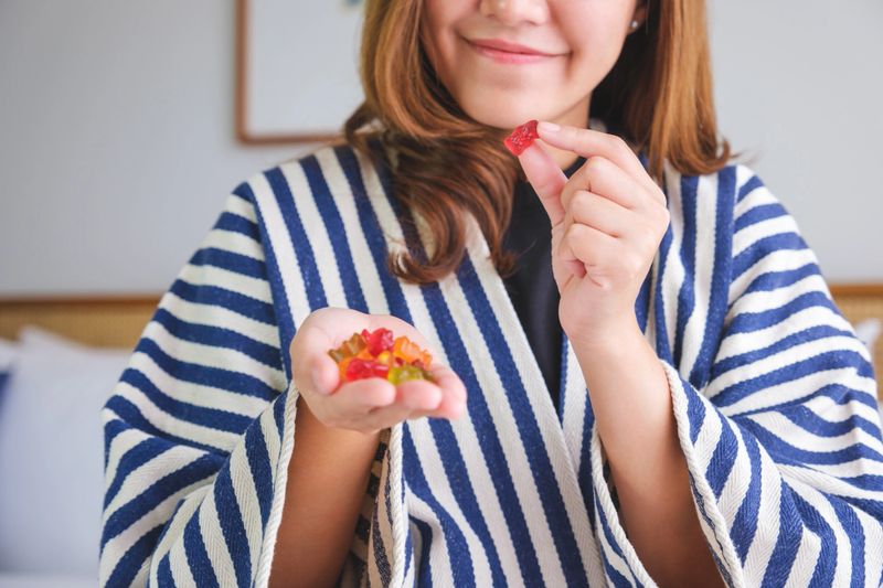 Closeup image of a young woman holding and eating jelly gummy bears