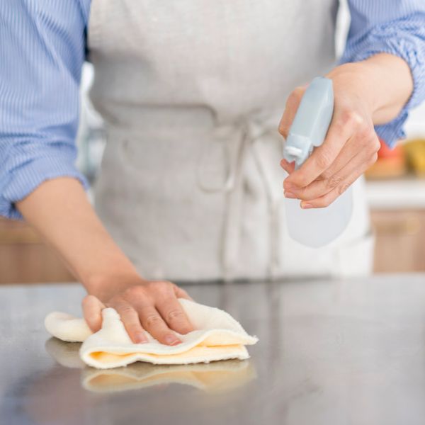 Person cleaning a surface with a cloth and spray bottle.