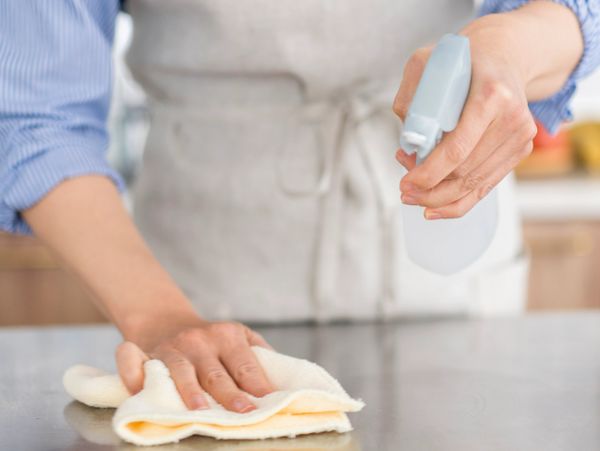 Person cleaning a surface with a spray bottle and cloth.