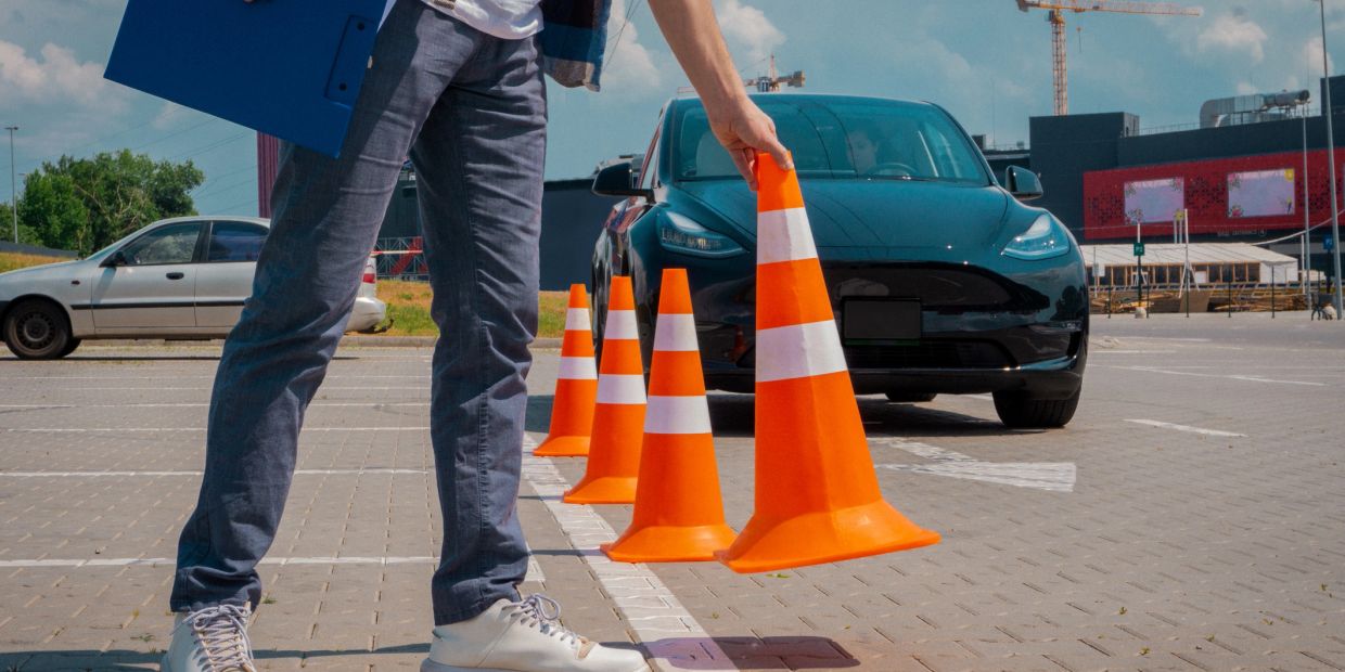 Person arranging traffic cones with a car in background.