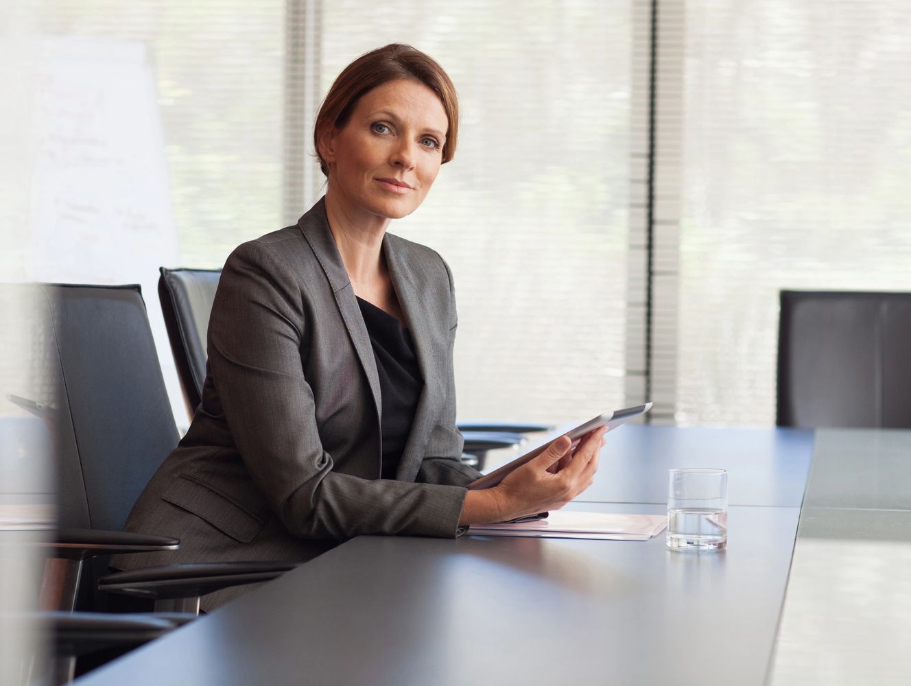 Confident businesswoman in a meeting room holding a tablet.