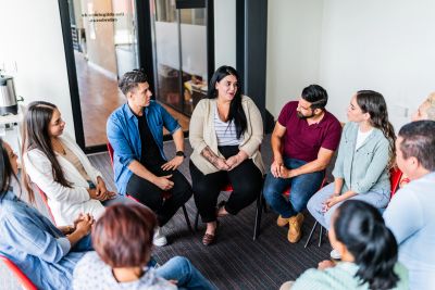 A group therapy session with people sitting in a circle and talking.