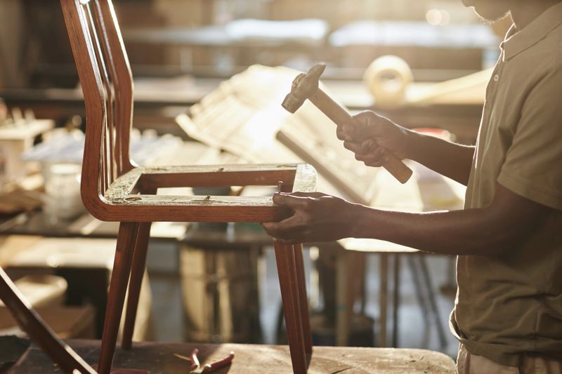 Close up of young black artisan fixing on furniture in sunlight, copy space