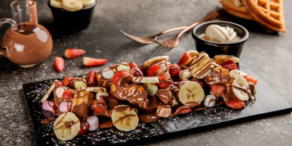 Waffles topped with strawberries, bananas, marshmallows, and drizzled chocolate.