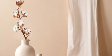 Minimalist cotton stems in a beige vase against a soft beige backdrop.