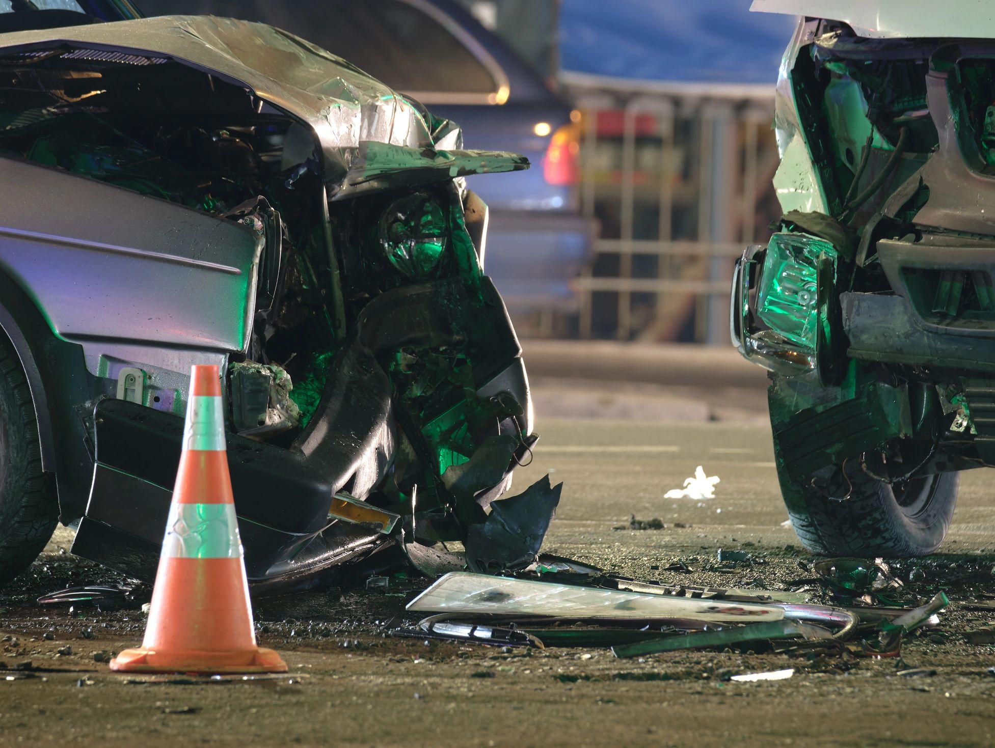 Two heavily damaged cars after a crash with an orange traffic cone.