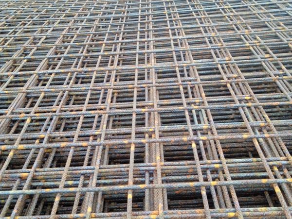 Rusty steel reinforcement bars arranged in a grid pattern.