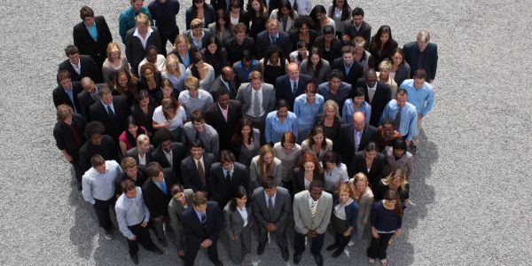 A diverse group of people standing closely together outdoors.