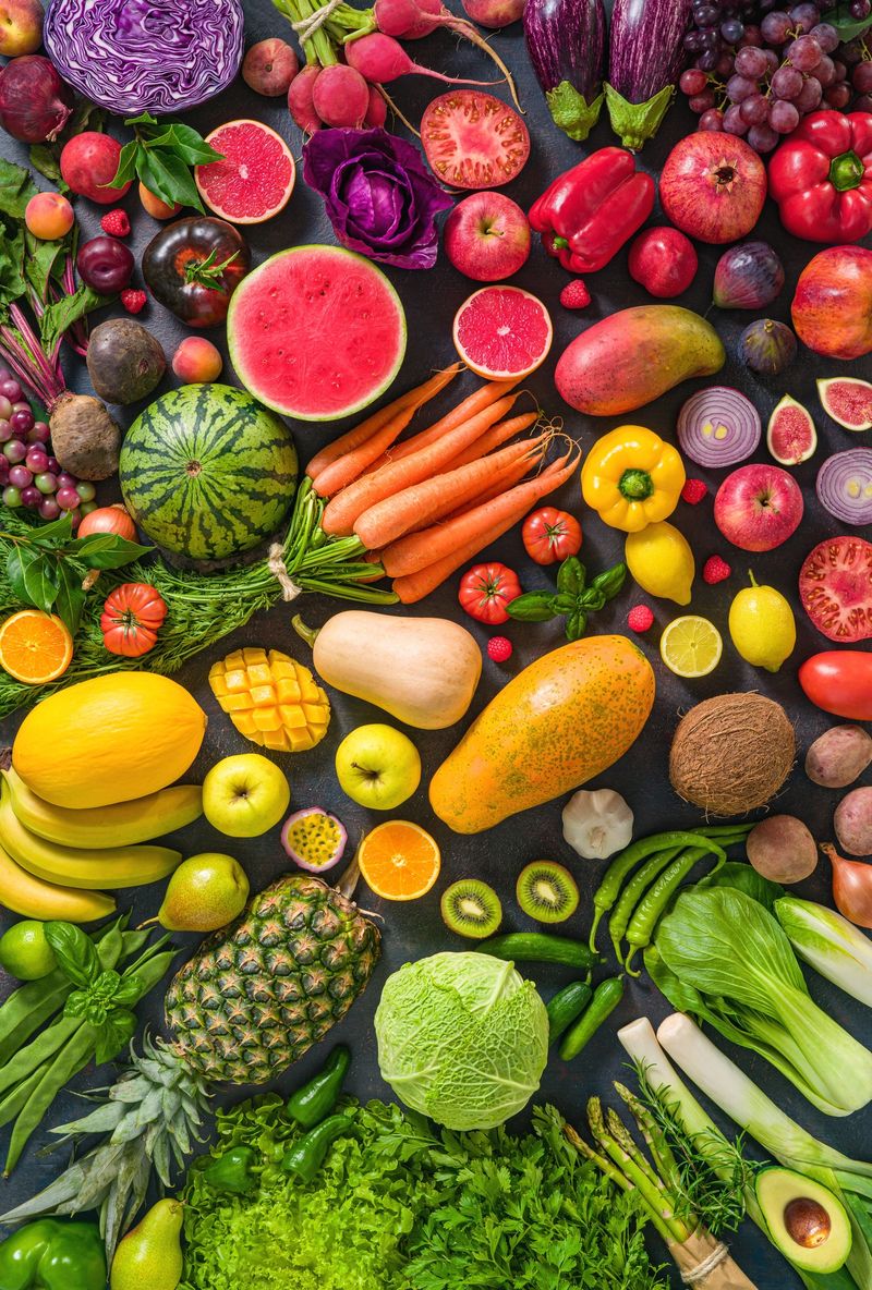 Colorful raw fruits and vegetables varied vegan food, vivid rainbow arrangement full frame background