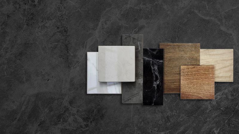 combination of interior material samples placed on dark black marble table including wooden ceramic floor tiles, luxury marble stones, elegance artificial stone tiles with blank space for design.