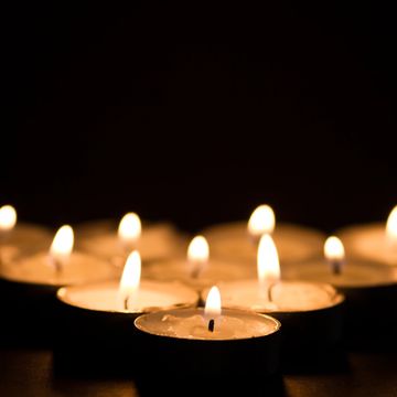 Lit tea light candles glowing in the dark.