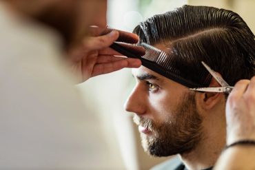 A man getting a haircut with scissors and comb.