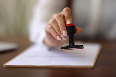 Hand holding a stamp on paper.
