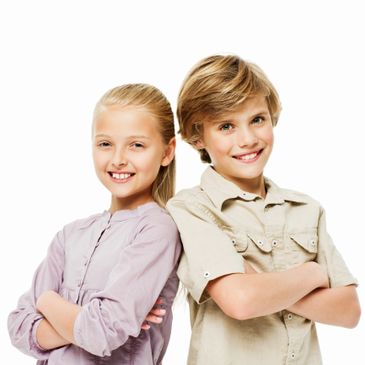 Smiling boy and girl standing back to back with arms crossed.
