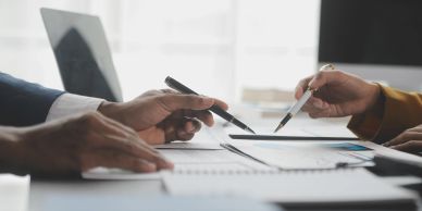 Two people reviewing documents and taking notes.