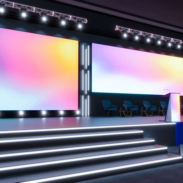 Modern conference stage with large colorful screens and seating.