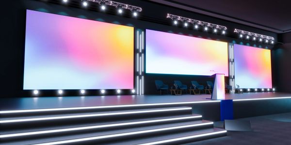Modern conference stage with large colorful screens and seating.
