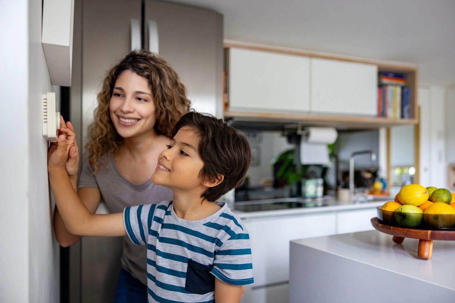 Black pencils in a gray holder next to a stack of white magazines with a camera in the background.