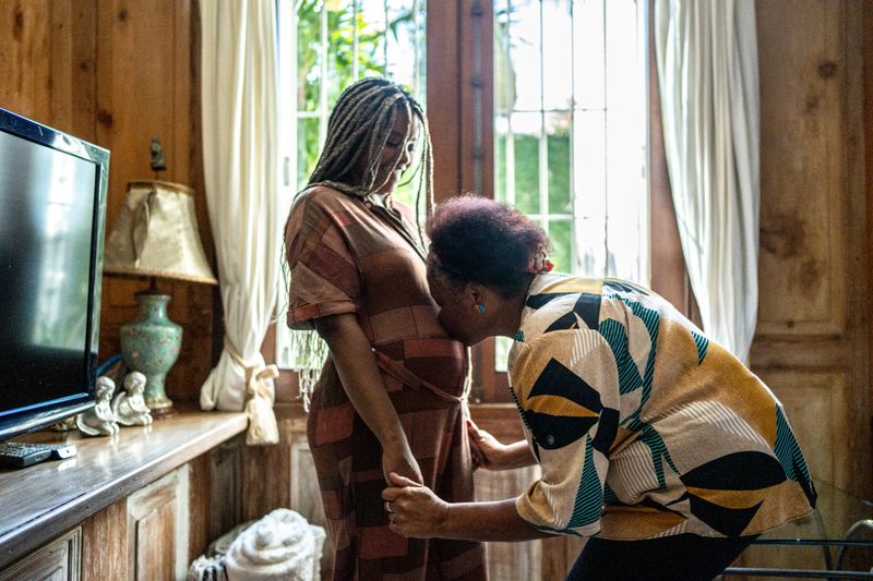 Mother kissing her pregnant daughter's abdomen at home