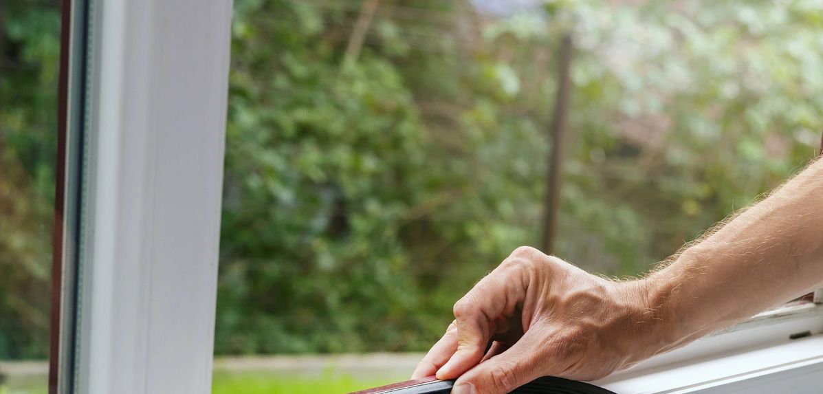 A person installing a rubber seal on a window frame.