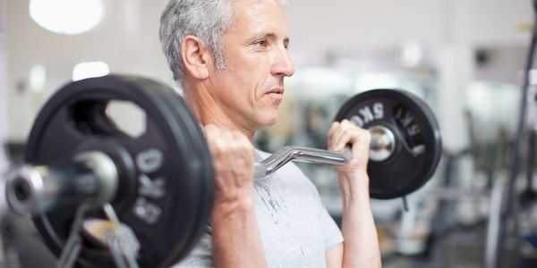 Middle-aged man lifting weights in a gym, focused on his workout.
