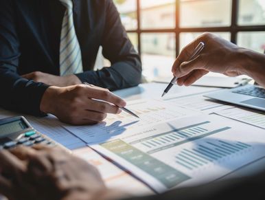 Two professionals analyzing financial charts and data in a meeting.
