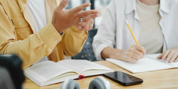Two people studying together with books and notes on a table.