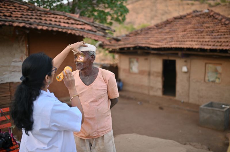 Image captures a significant moment as a female doctor conducts an eye examination on a senior man. This image showcases the importance of comprehensive healthcare and the dedication of medical professionals in rural communities. The doctor engages in a brief conversation with the senior man, inquiring about his eye health, any specific concerns, or changes in his vision. With active listening, the doctor attentively absorbs the man's responses, ensuring a comprehensive understanding of his condition.