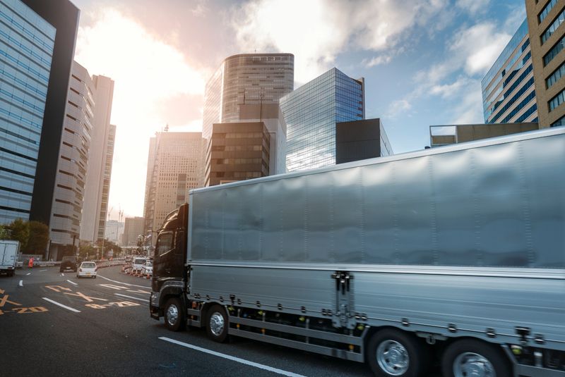 Freight delivery truck with a slight motion blur driving across a modern city between high skyscrapers