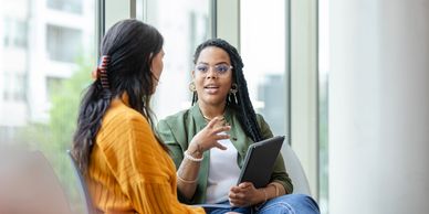 Two women engaged in a serious conversation indoors.