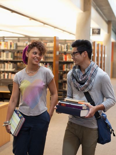 Two young adults walking in a library.
