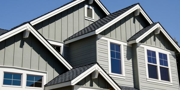 Modern house exterior with grey siding and pitched roofs.