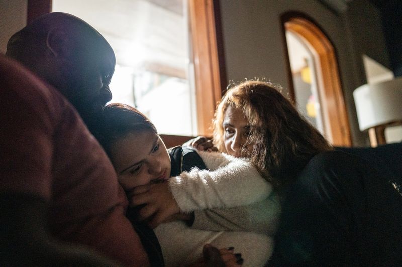 Parents hug their teenage daughter, who has down syndrome, at home