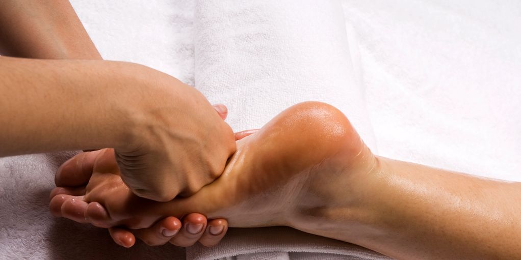 Massage du pied sur une serviette blanche.
