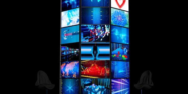 A tall digital display tower with various news and data visuals, flanked by two modern chairs.