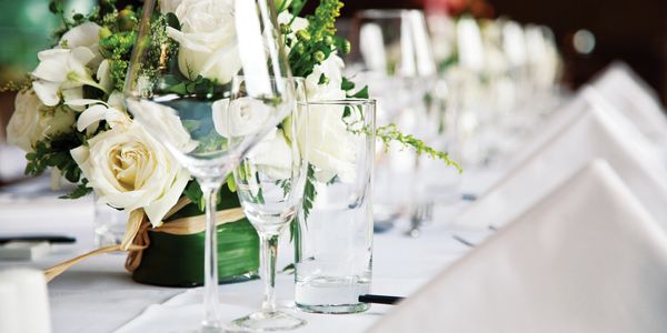 Elegant table setting with white roses and glassware for a formal event.