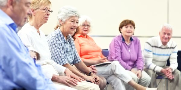 Group of elderly people sitting in a circle, engaged in a discussion.