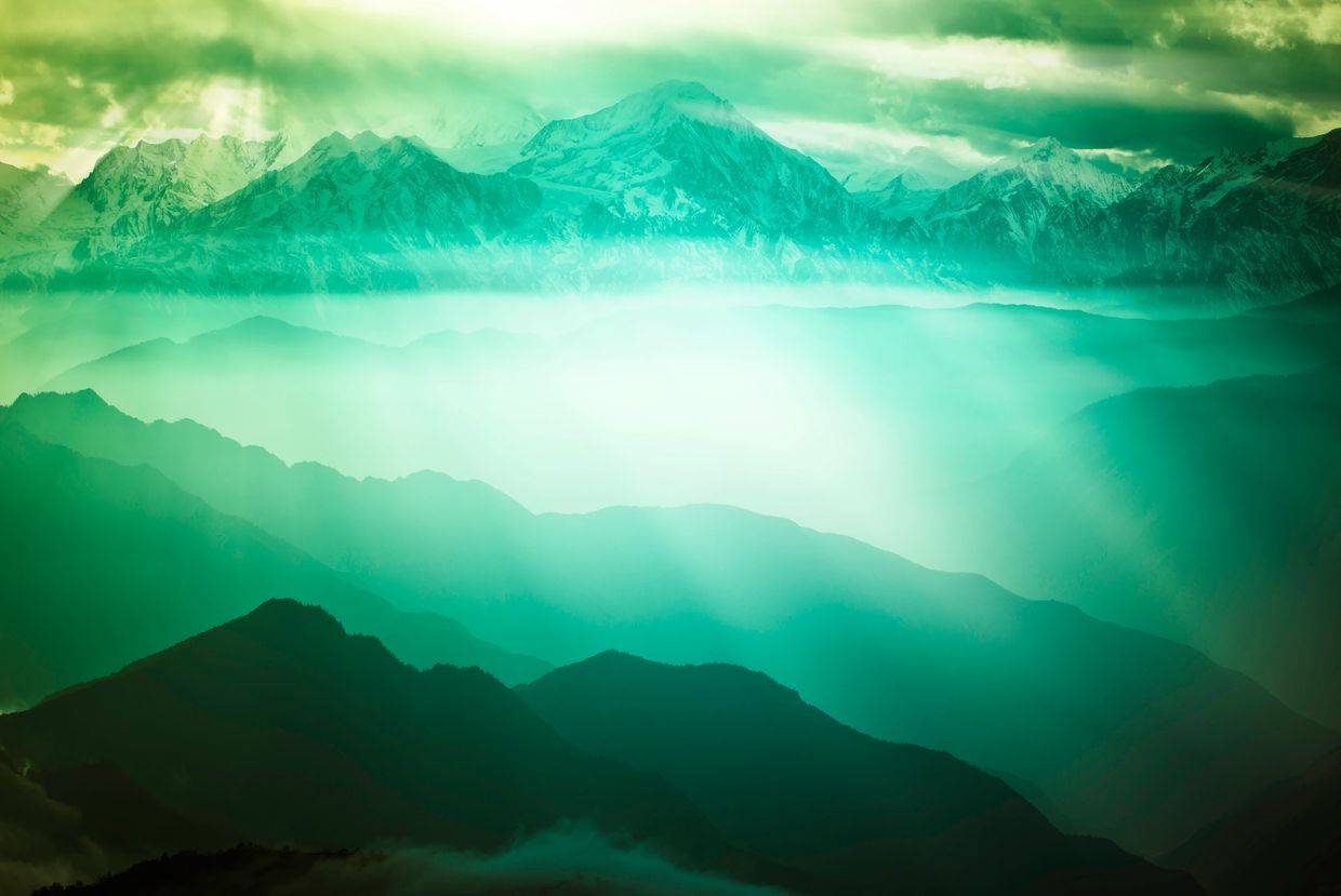 Sun rays pierce through misty mountain ranges, creating a mystical green ambiance.
