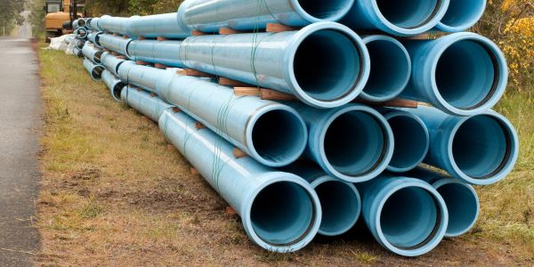 Stack of blue PVC pipes outdoors.