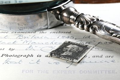 A vintage stamp and a magnifying glass on a handwritten document.