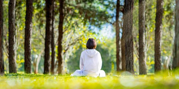 A woman sitting in the forest contemplating.