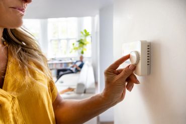 Woman adjusting a thermostat on the wall.