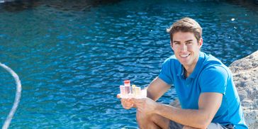 A man sitting beside a swimming pool