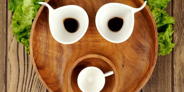 Wooden tray with cups arranged to resemble a surprised face with lettuce as ears.