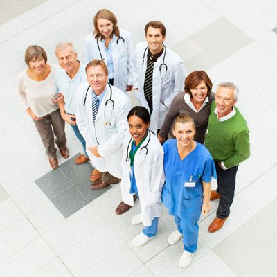 Doctors and patients smiling together in a bright hospital lobby.