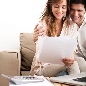 Happy couple reviewing documents together on a couch.