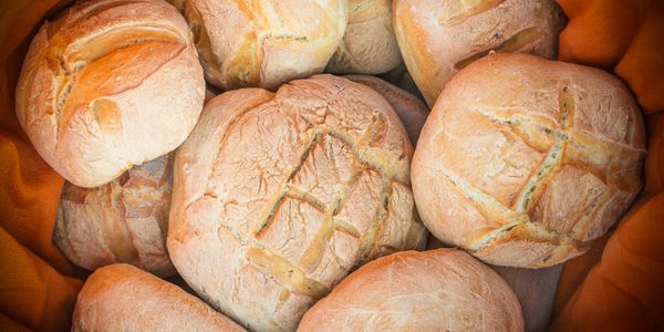 Freshly baked crusty bread rolls with distinct scoring patterns.